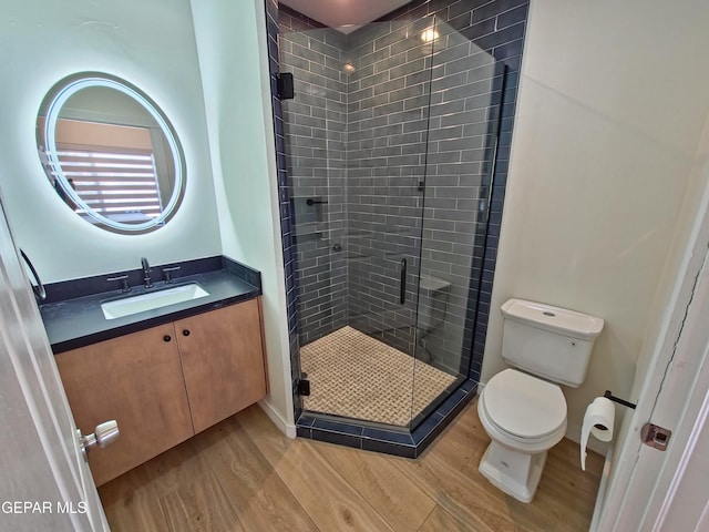 bathroom with hardwood / wood-style flooring, vanity, toilet, and a shower with door