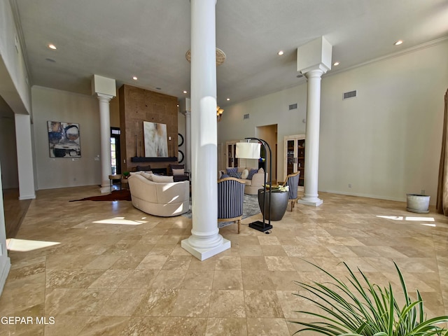 living room with crown molding, a fireplace, a high ceiling, and decorative columns