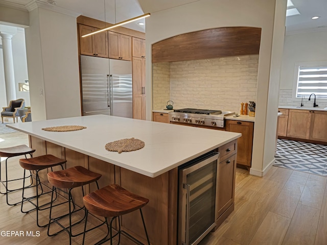 kitchen with tasteful backsplash, a kitchen island, stainless steel built in fridge, wine cooler, and hanging light fixtures