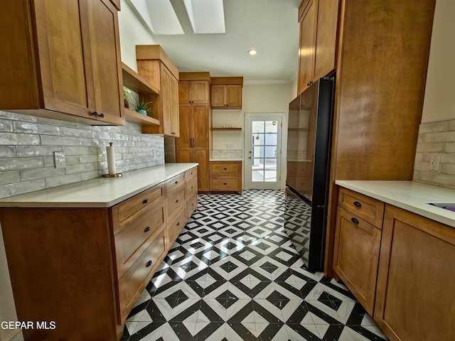 kitchen with black refrigerator, tasteful backsplash, and ornamental molding