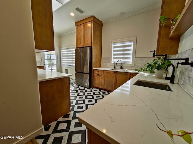 kitchen featuring ornamental molding, sink, and stainless steel refrigerator