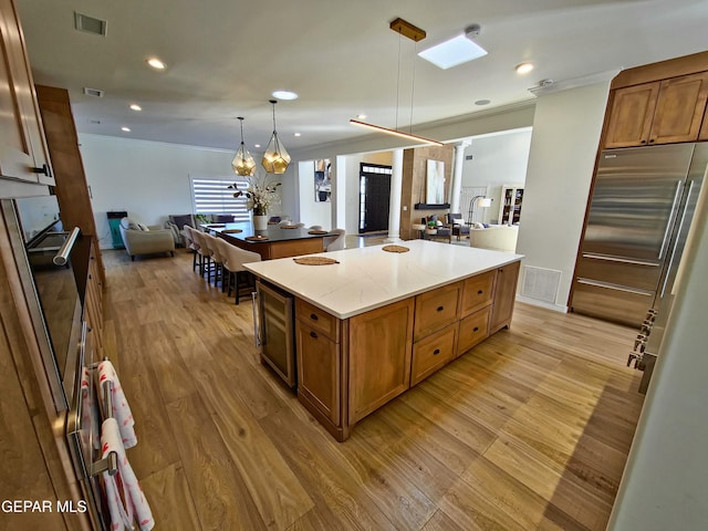 kitchen featuring oven, stainless steel built in fridge, decorative light fixtures, a kitchen island, and a chandelier