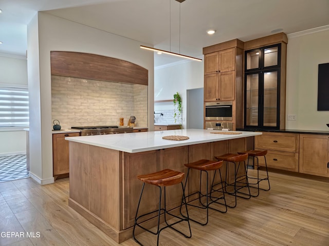 kitchen with oven, light hardwood / wood-style floors, a spacious island, and hanging light fixtures