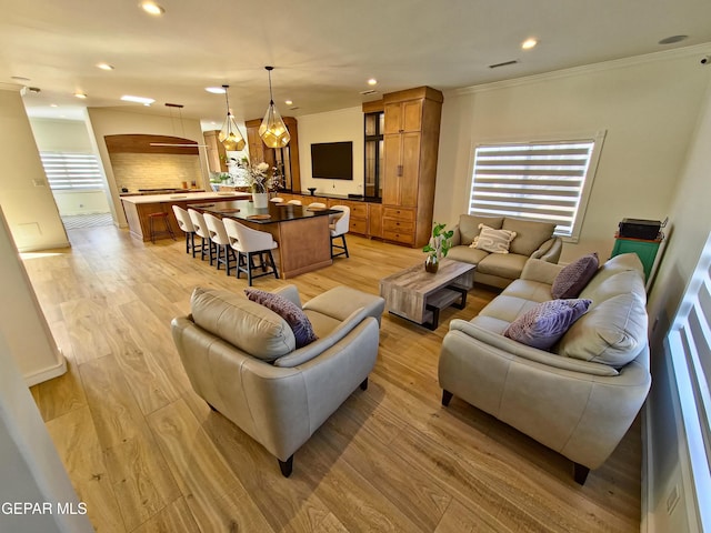 living room with plenty of natural light, light hardwood / wood-style floors, and ornamental molding