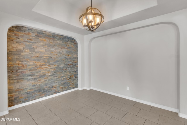 spare room featuring tile patterned floors, a notable chandelier, and a raised ceiling