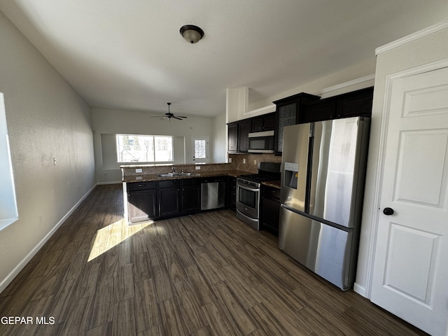 kitchen with appliances with stainless steel finishes, ceiling fan, dark hardwood / wood-style floors, decorative backsplash, and sink