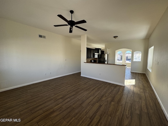 unfurnished living room featuring ceiling fan and dark wood-type flooring