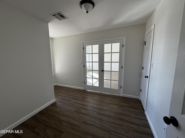 spare room featuring french doors and dark hardwood / wood-style floors