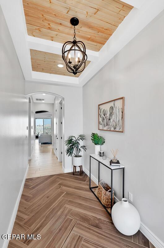 corridor featuring an inviting chandelier, parquet floors, and wood ceiling