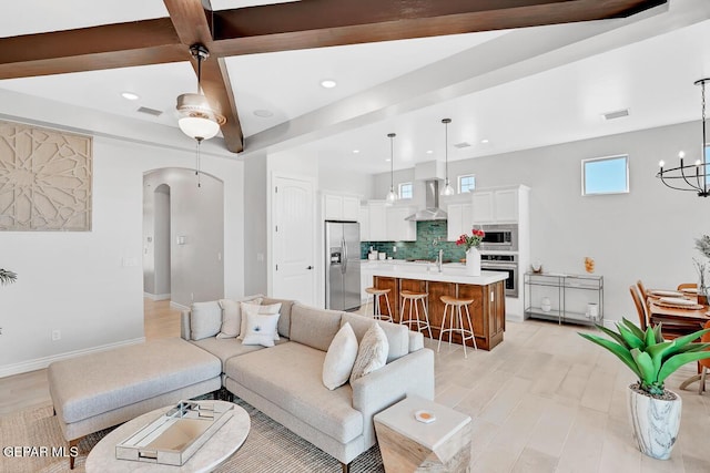 living room featuring beamed ceiling, a notable chandelier, sink, and light hardwood / wood-style flooring