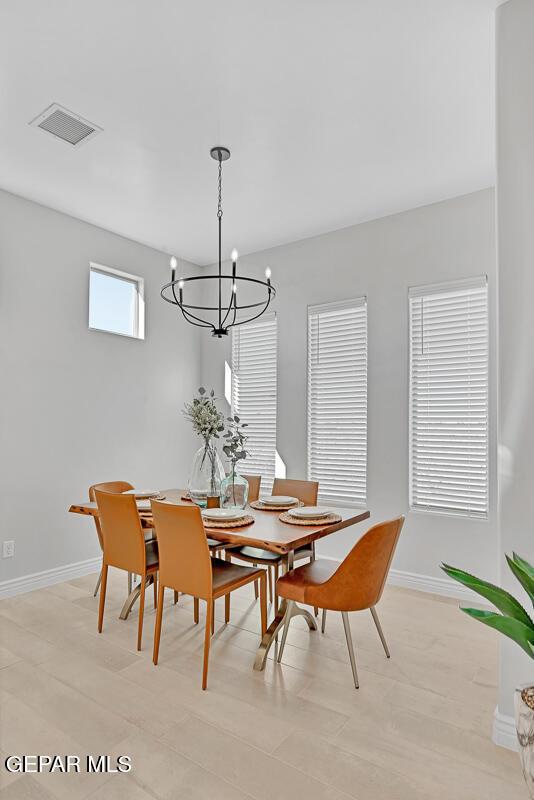 dining area with light hardwood / wood-style flooring and a notable chandelier