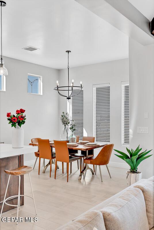 dining area featuring a healthy amount of sunlight, light wood-type flooring, and an inviting chandelier