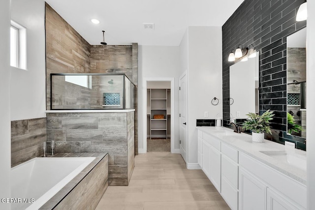 bathroom featuring shower with separate bathtub, vanity, and tile walls