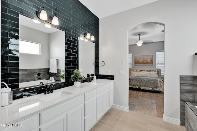 bathroom featuring ceiling fan, hardwood / wood-style floors, vanity, and tile walls