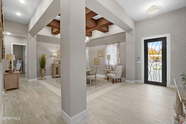 entrance foyer with a towering ceiling, light hardwood / wood-style flooring, beamed ceiling, and coffered ceiling