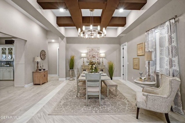 dining area with a high ceiling, coffered ceiling, an inviting chandelier, beamed ceiling, and light hardwood / wood-style floors