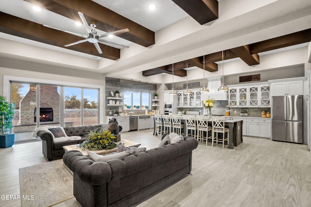 living room featuring beam ceiling, ceiling fan, and a fireplace