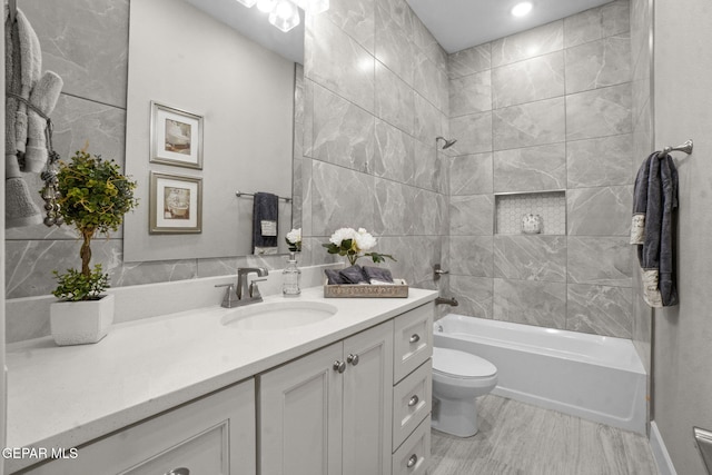 full bathroom with vanity, toilet, tiled shower / bath, and tile walls