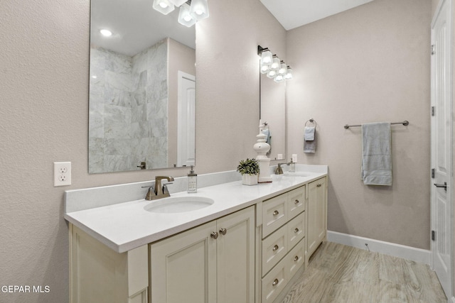 bathroom with hardwood / wood-style floors, vanity, and tiled shower