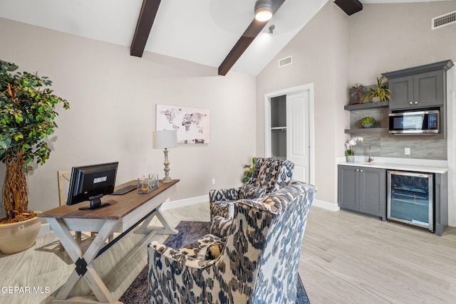 home office with light wood-type flooring, beverage cooler, ceiling fan, beam ceiling, and high vaulted ceiling