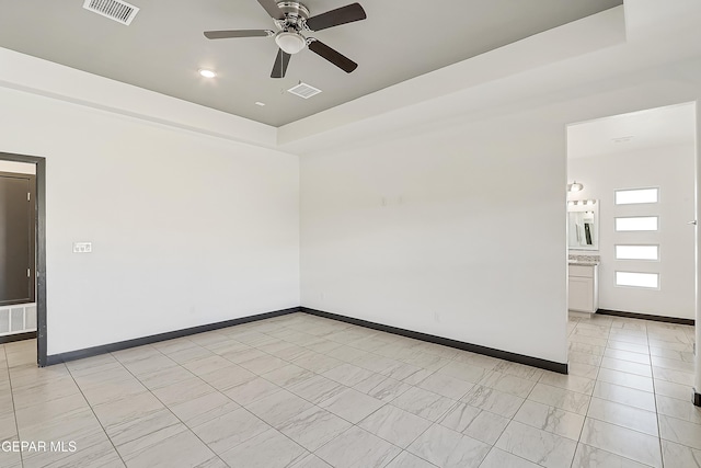 unfurnished room featuring light tile patterned floors, a tray ceiling, and ceiling fan