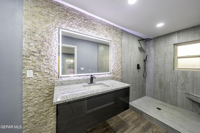 bathroom with a tile shower, vanity, and hardwood / wood-style flooring