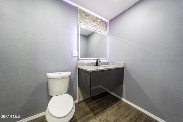 bathroom with toilet, vanity, and hardwood / wood-style flooring