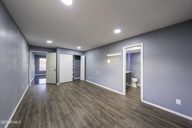 unfurnished bedroom featuring dark hardwood / wood-style floors, a closet, and ensuite bath