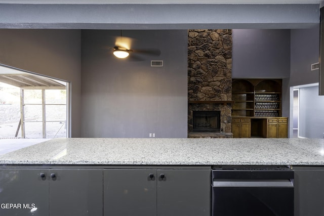 kitchen with light stone countertops, a fireplace, and ceiling fan