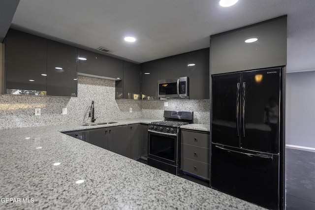 kitchen featuring black refrigerator, light stone countertops, gas range, sink, and gray cabinets