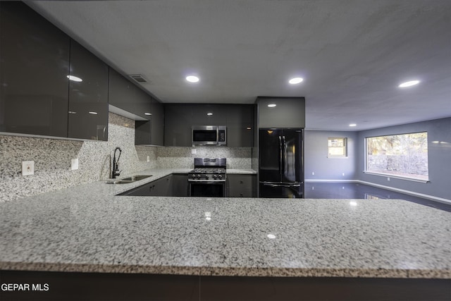 kitchen featuring gray cabinetry, sink, light stone countertops, tasteful backsplash, and stainless steel appliances