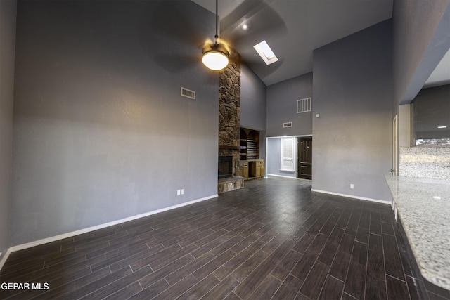 unfurnished living room featuring ceiling fan, a fireplace, high vaulted ceiling, and a skylight