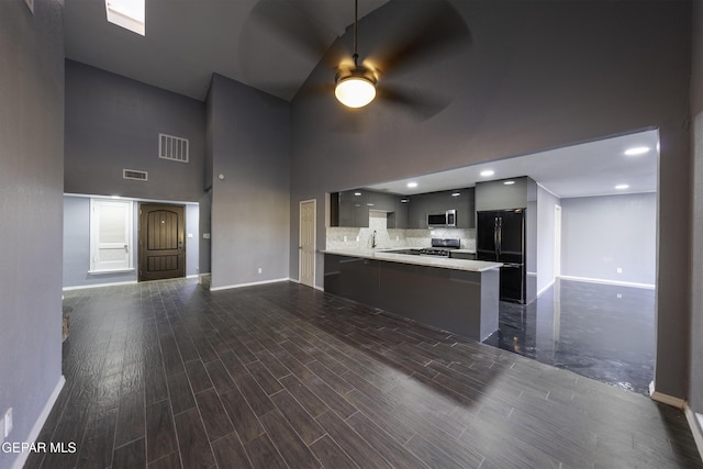 kitchen featuring sink, kitchen peninsula, stainless steel appliances, and a high ceiling