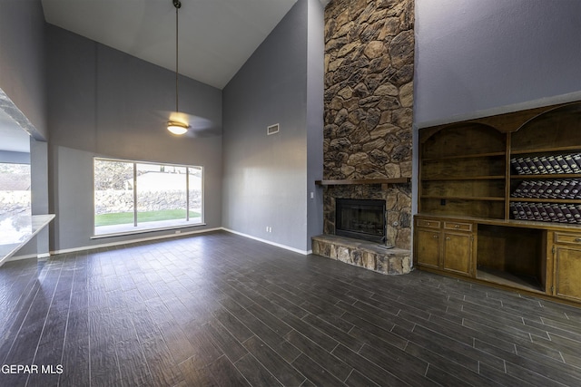 unfurnished living room featuring a fireplace, dark hardwood / wood-style floors, high vaulted ceiling, and a healthy amount of sunlight