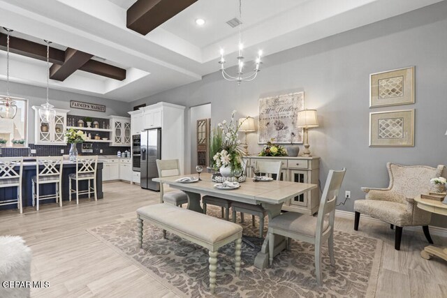 dining area featuring a chandelier, beam ceiling, and light hardwood / wood-style floors