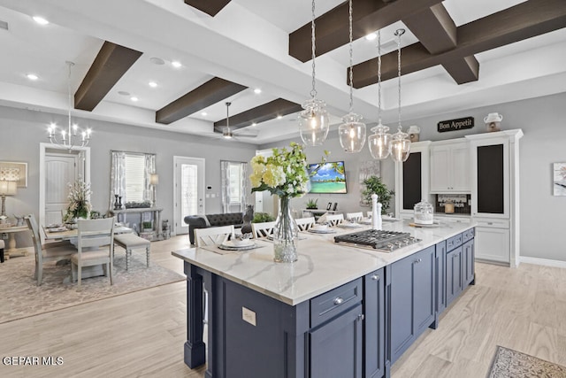 kitchen with blue cabinets, ceiling fan, decorative light fixtures, a kitchen island, and white cabinetry