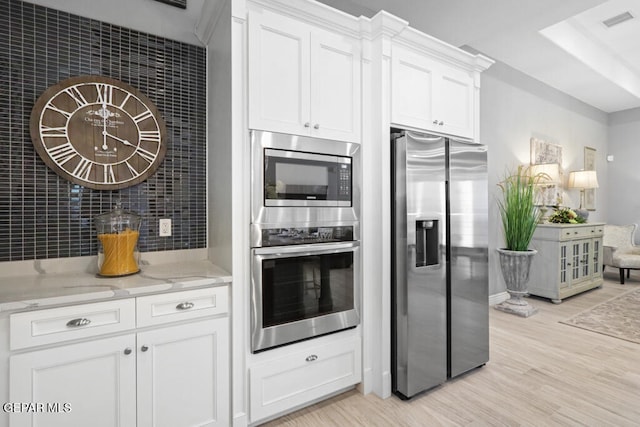 kitchen featuring light stone countertops, white cabinetry, stainless steel appliances, and light wood-type flooring