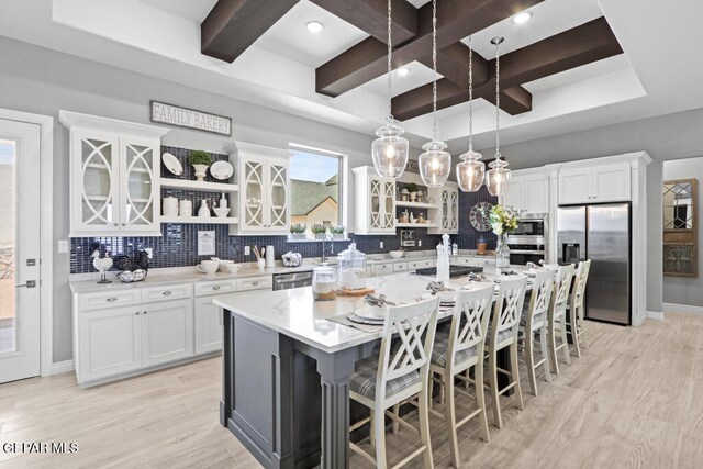 kitchen with stainless steel appliances, pendant lighting, a center island with sink, white cabinets, and a breakfast bar area