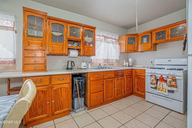 kitchen featuring gas range gas stove, sink, and light tile patterned floors