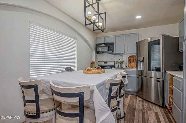 kitchen featuring gray cabinetry, dark wood-type flooring, an inviting chandelier, decorative light fixtures, and appliances with stainless steel finishes