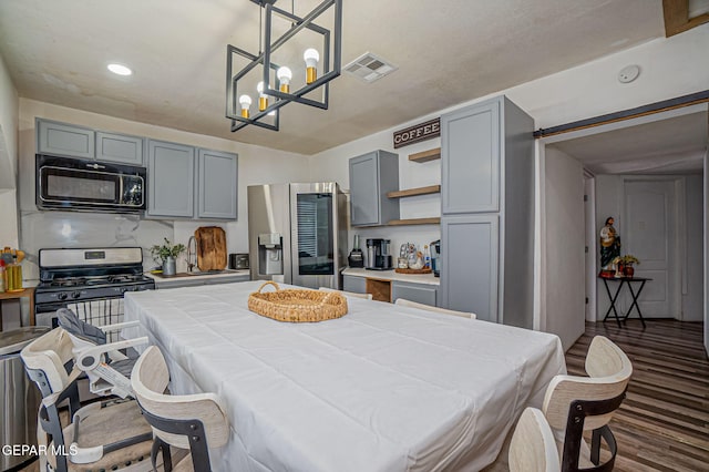 kitchen with appliances with stainless steel finishes, gray cabinets, and pendant lighting