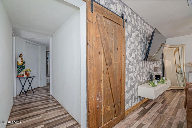 hall with a barn door and dark hardwood / wood-style floors