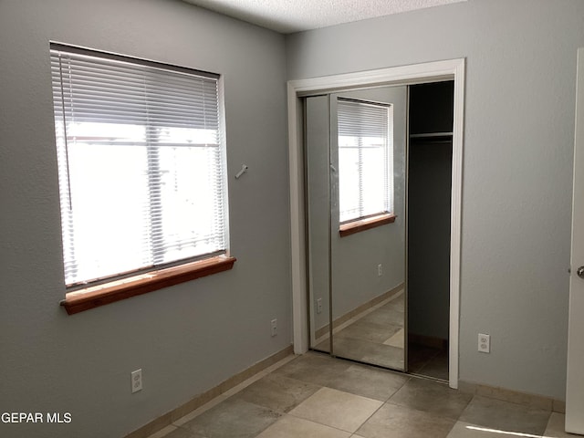 unfurnished bedroom featuring a closet, light tile patterned floors, and a textured ceiling