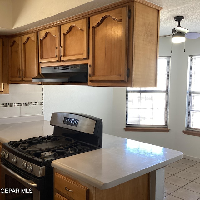 kitchen featuring decorative backsplash, a textured ceiling, ceiling fan, light tile patterned floors, and black gas range