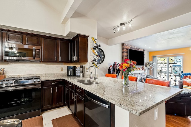 kitchen featuring sink, stainless steel appliances, kitchen peninsula, decorative backsplash, and light tile patterned floors