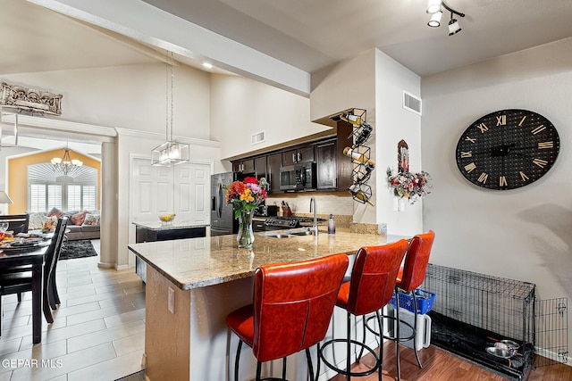 kitchen with kitchen peninsula, stainless steel appliances, sink, a notable chandelier, and a breakfast bar area