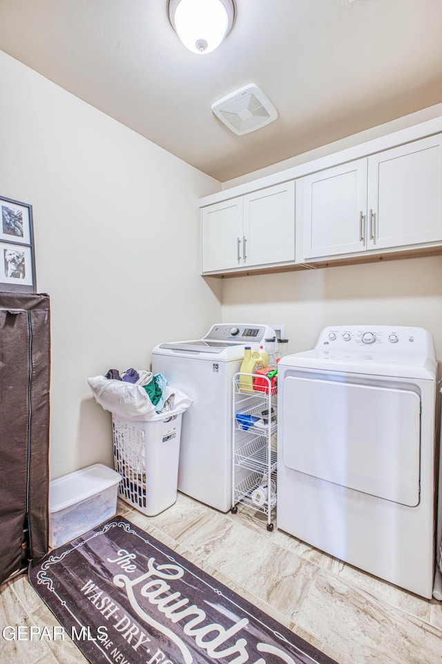 clothes washing area with cabinets and washing machine and dryer