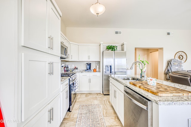 kitchen featuring appliances with stainless steel finishes, tasteful backsplash, sink, a center island with sink, and white cabinetry