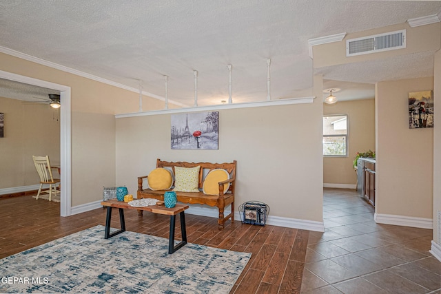 living area featuring a textured ceiling, ceiling fan, and crown molding