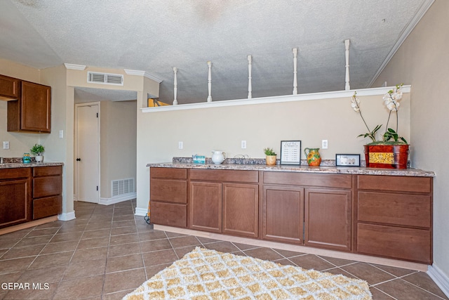 kitchen with tile patterned floors, crown molding, and a textured ceiling